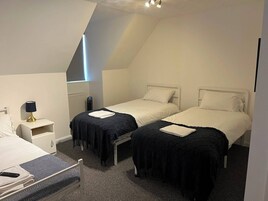 Una habitación con dos camas, una mesita de noche, una lámpara y un radiador.