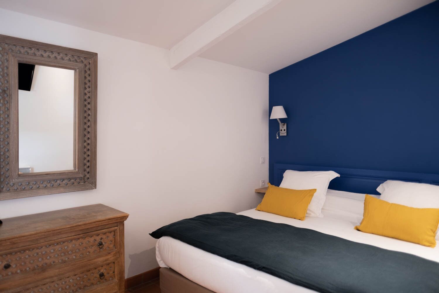 Ein Schlafzimmer mit Bett, Schminktisch, Spiegel und Wandlampe.