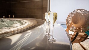 Un bain à remous, deux coupes de champagne, un fauteuil en osier et une vue sur la mer.