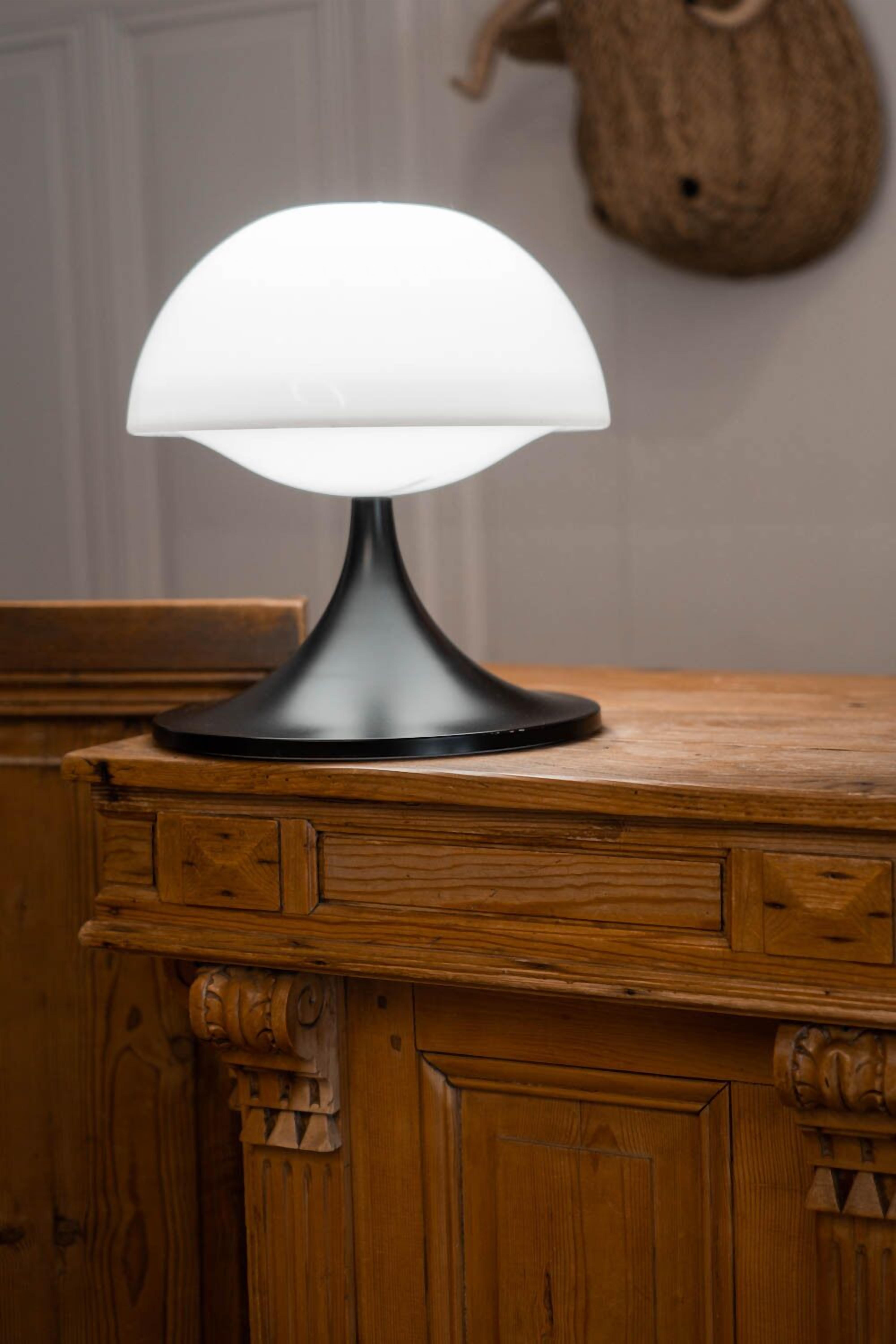 Una lampada da tavolo con paralume bianco su un tavolo di legno.