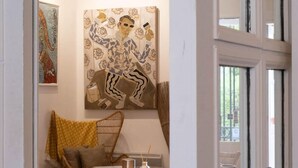 Une pièce avec une table en bois, une chaise, un vase et un tableau accroché au mur.