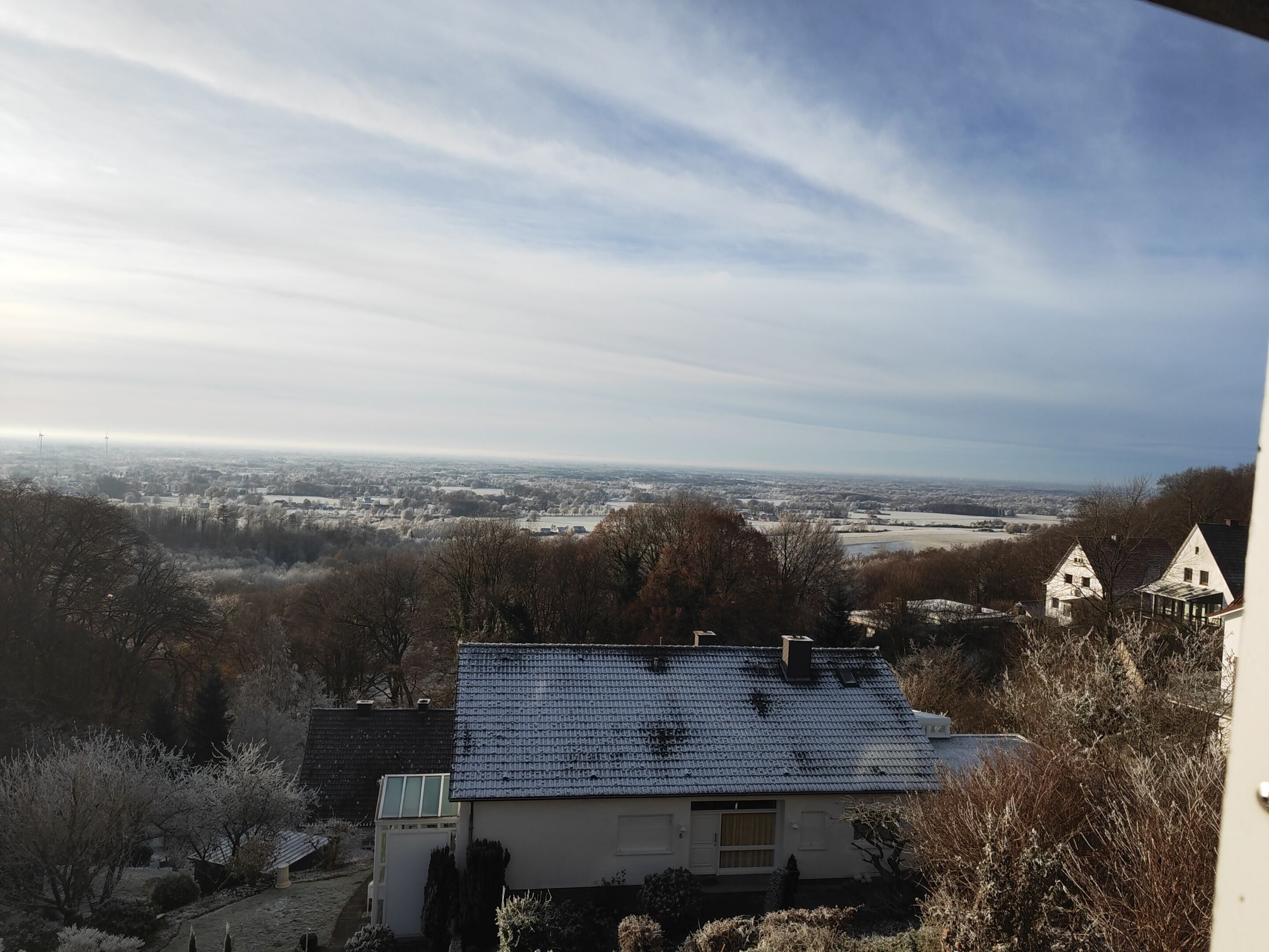A house with a sloped roof, a small attached garage, and a view of a distant landscape.