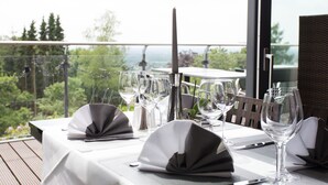 A table set for dining with a view of a forested landscape. - Hotel Bismarckhöhe (Tecklenburg)