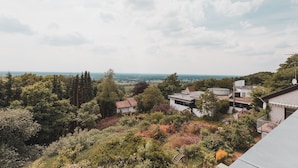 A residential area with modern houses surrounded by dense greenery and a distant view of the sea. - Hotel Bismarckhöhe (Tecklenburg)
