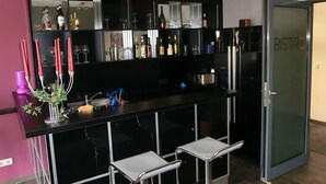 A modern kitchen with a black countertop, bar stools, and a minibar. - Hotel Bismarckhöhe (Tecklenburg)