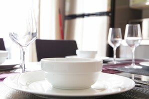 Una mesa de comedor con un tazón blanco, dos copas de vino y una silla negra.
