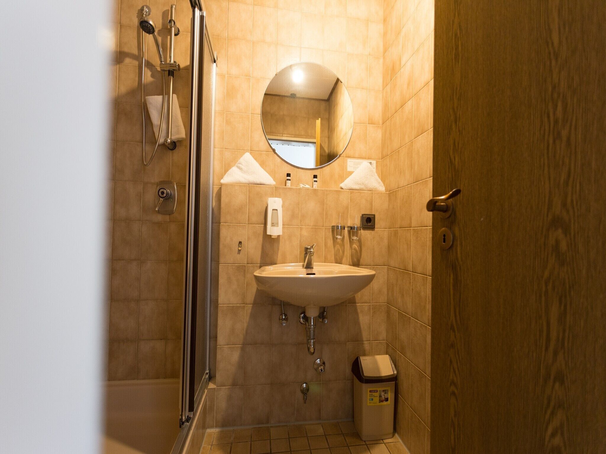 A bathroom with a sink, mirror, towel rack, and shower.