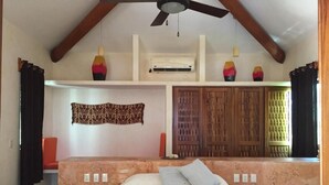 A bedroom with a bed, two bedside tables, a ceiling fan, a wall-mounted air conditioner, and a wooden wardrobe. -  CASA MONARCA. Self sustained house in La Ropa, Zihuatanejo, Gro. México. (Zihuatanejo)