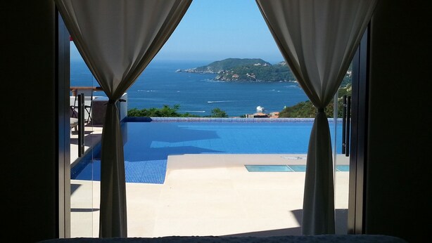 A room with a view of the sea through curtains, a pool, and a chair. -  CASA MONARCA. Self sustained house in La Ropa, Zihuatanejo, Gro. México. (Zihuatanejo)