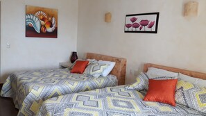 A hotel room with two beds, patterned bedding, and artwork on the walls.