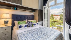 A bedroom with a bed, bedside table, lamp, and a view of the outside balcony. - UNIQUE & URBAN 4* House DelMarco apt @ TOP CENTRAL LOCATION (Split)