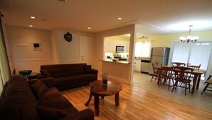 A living room with a sofa, a coffee table, and a dining area with a table and chairs.