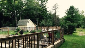 A backyard with a wooden deck, concrete steps, a small shed, and a fenced area with outdoor furniture.