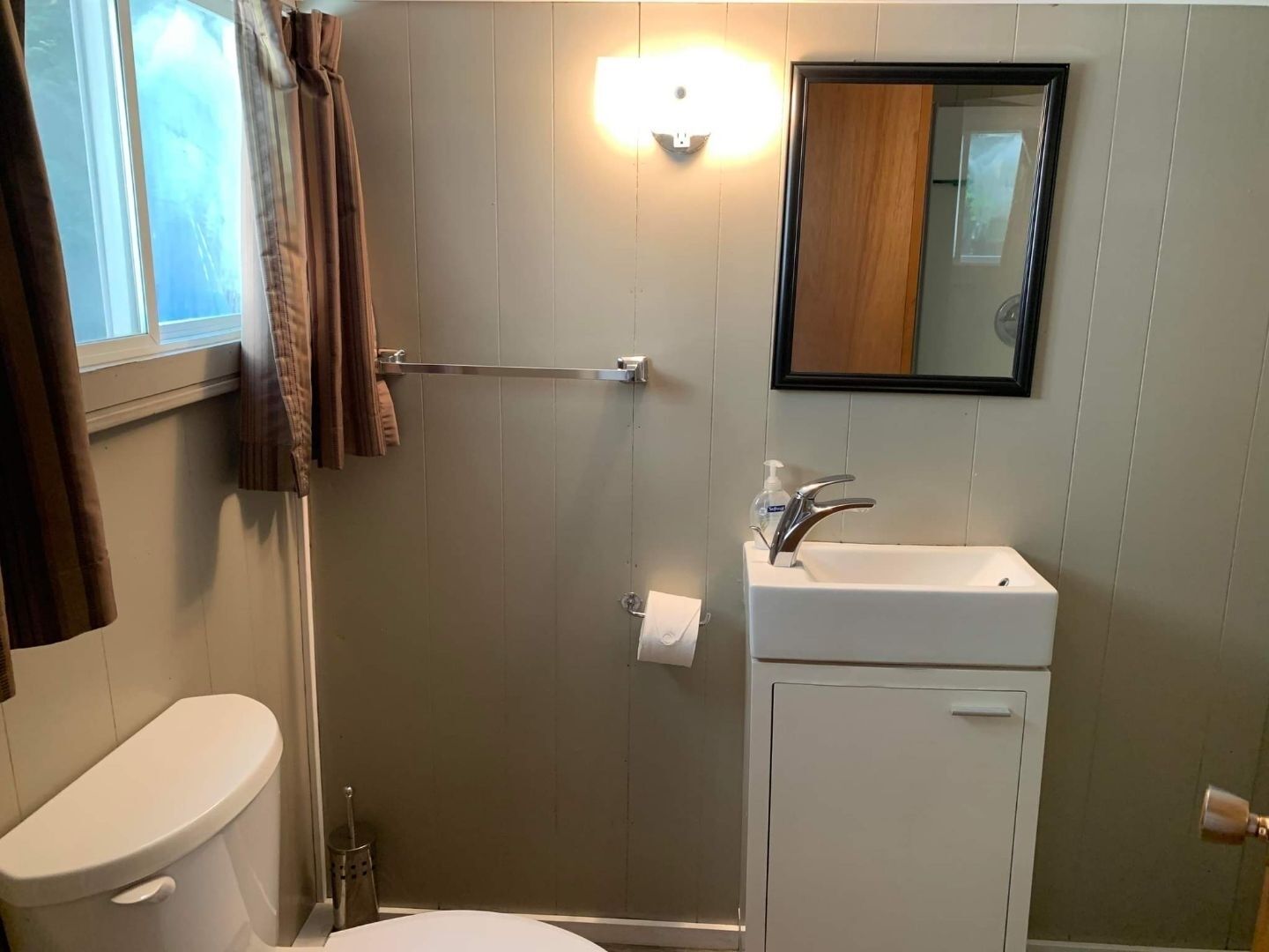 A bathroom with a toilet, a sink, a shower, and a mirror.