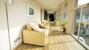 A corridor with a sofa, potted plants, and a framed picture on the wall. - Amalia Bakery Home (Gallarate)