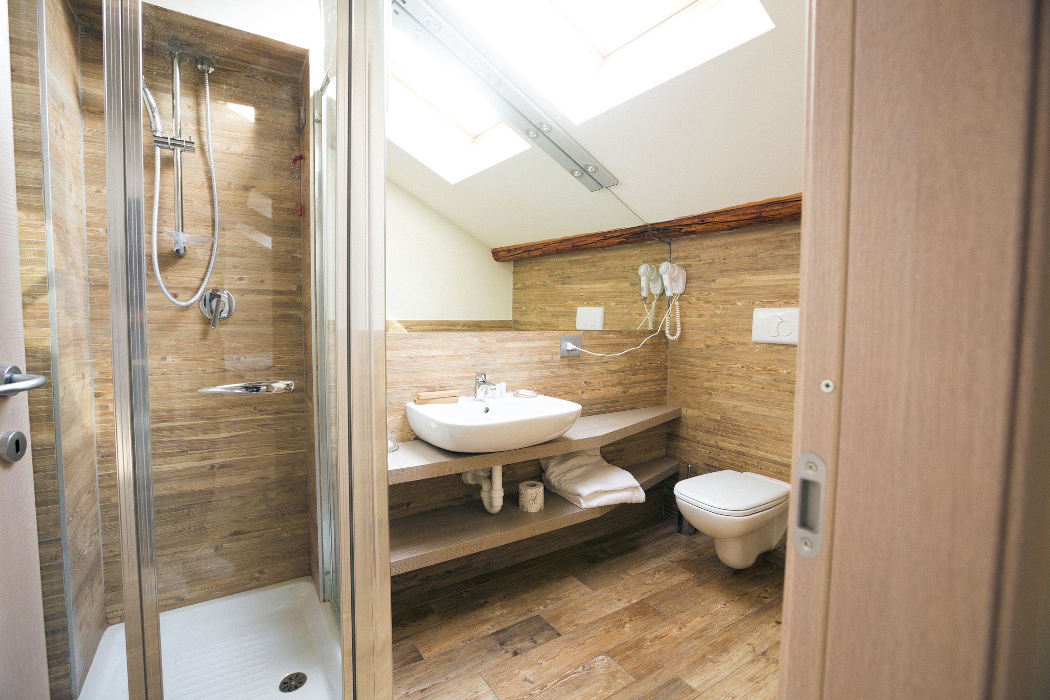 A modern bathroom with a glass-enclosed shower, a wooden vanity with a sink, and a toilet.