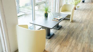 A modern office space with a large window, a table with a plant, and two chairs. - Amalia Bakery Home (Gallarate)