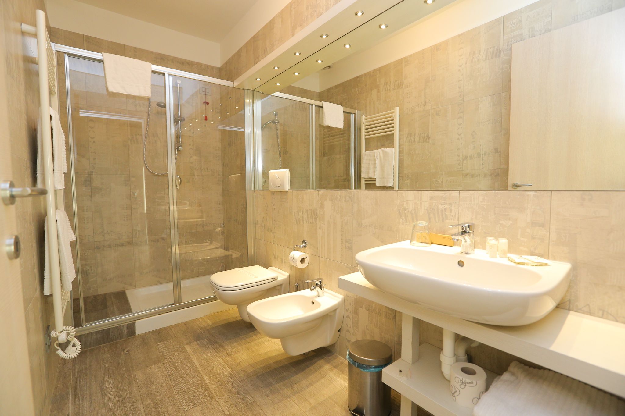 Ein modernes Badezimmer mit einer Duschkabine, einer Toilette, einem Bidet und einem großen Waschbecken.