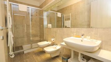 Ein modernes Badezimmer mit einer Duschkabine, einer Toilette, einem Bidet und einem großen Waschbecken.