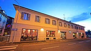 A two-story building with large windows and a cafe on the ground floor. - Amalia Bakery Home (Gallarate)
