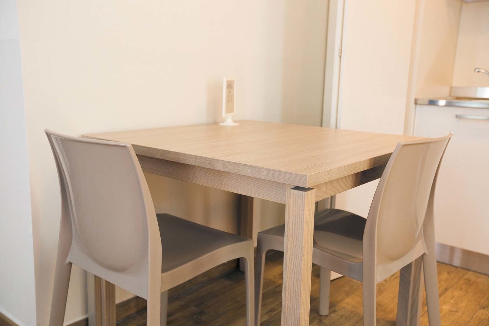 A small, modern kitchen with a wooden table and matching chairs.