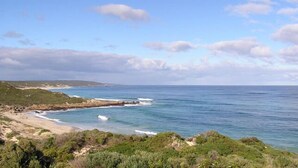 A coastal landscape with a beach, rocky outcrops, and vegetation.