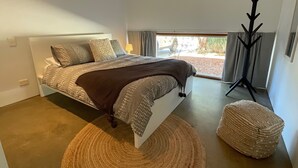 A modern bedroom with a large bed, a floor lamp, and a view of the outdoors.