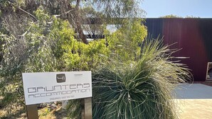 A sign for a guest accommodation with a contact number.