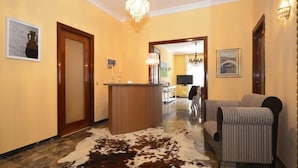Un hall de hotel con mostrador de recepción, un sofá, una araña de cristal y un tapiz de cuero de vaca.