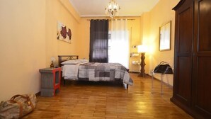 Un dormitorio con cama, mesita de noche, lámpara, armario y un cuadro en la pared.