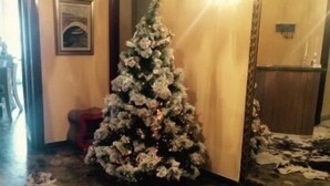 Un árbol de Navidad en el vestíbulo de un hotel, con un espejo grande que refleja el árbol.