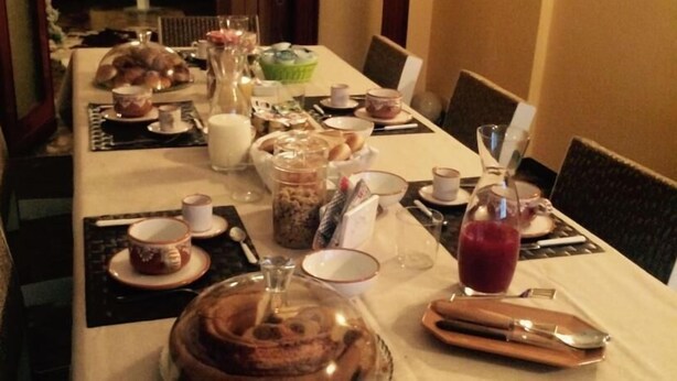 Una mesa de comedor dispuesta con diferentes platos, incluyendo un pastel, tazones y vasos.