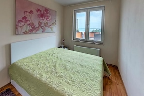 Una camera da letto con un letto, una finestra, un termosifone e un quadro appeso al muro.