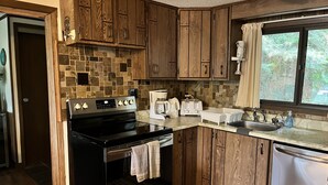 Una cocina con armarios de madera, una estufa negra, un café, un tostador y un lavabo.