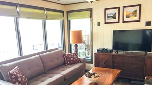 Una sala de estar con un sofá, una mesa de centro con un recipiente de bocadillos, un televisor y un mueble.
