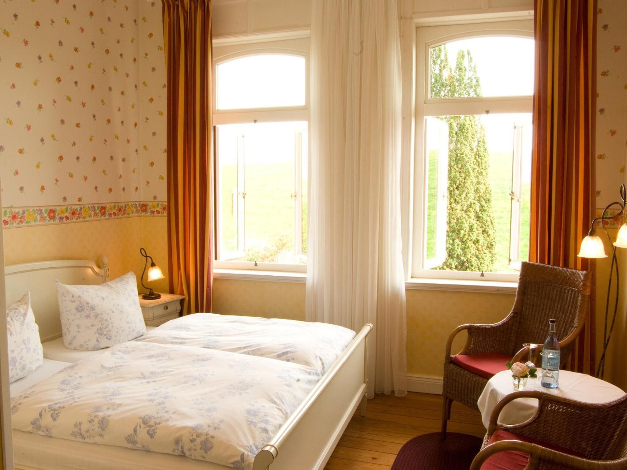A bedroom with a bed, two bedside tables, a chair, and a window with curtains.