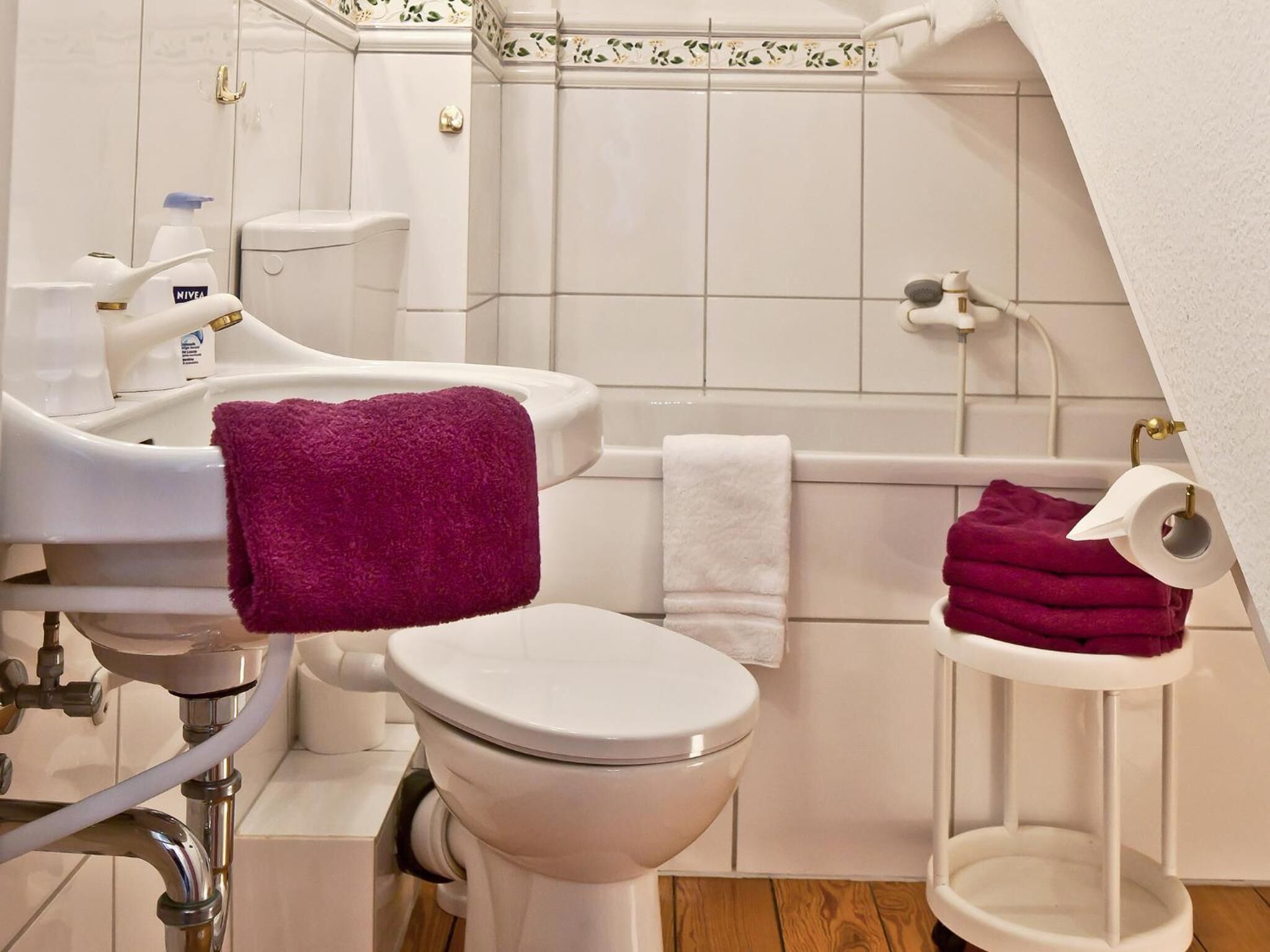 A bathroom with a toilet, sink, and bathtub. There are towels and toiletries visible.