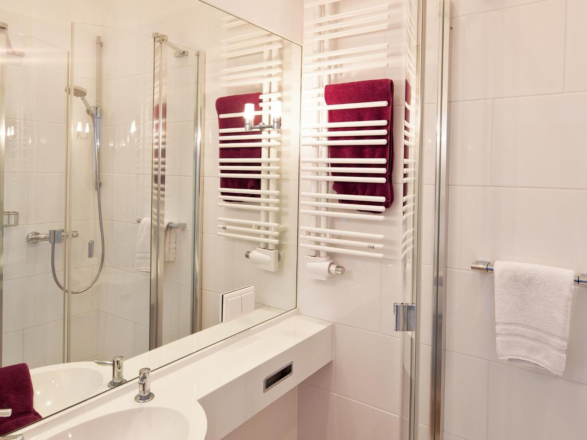 Un baño moderno con cabina de ducha de vidrio, un lavabo blanco y un espejo.