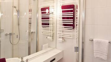 Un baño moderno con cabina de ducha de vidrio, un lavabo blanco y un espejo.