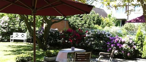 A patio area with outdoor seating, including tables and chairs, under a large umbrella.