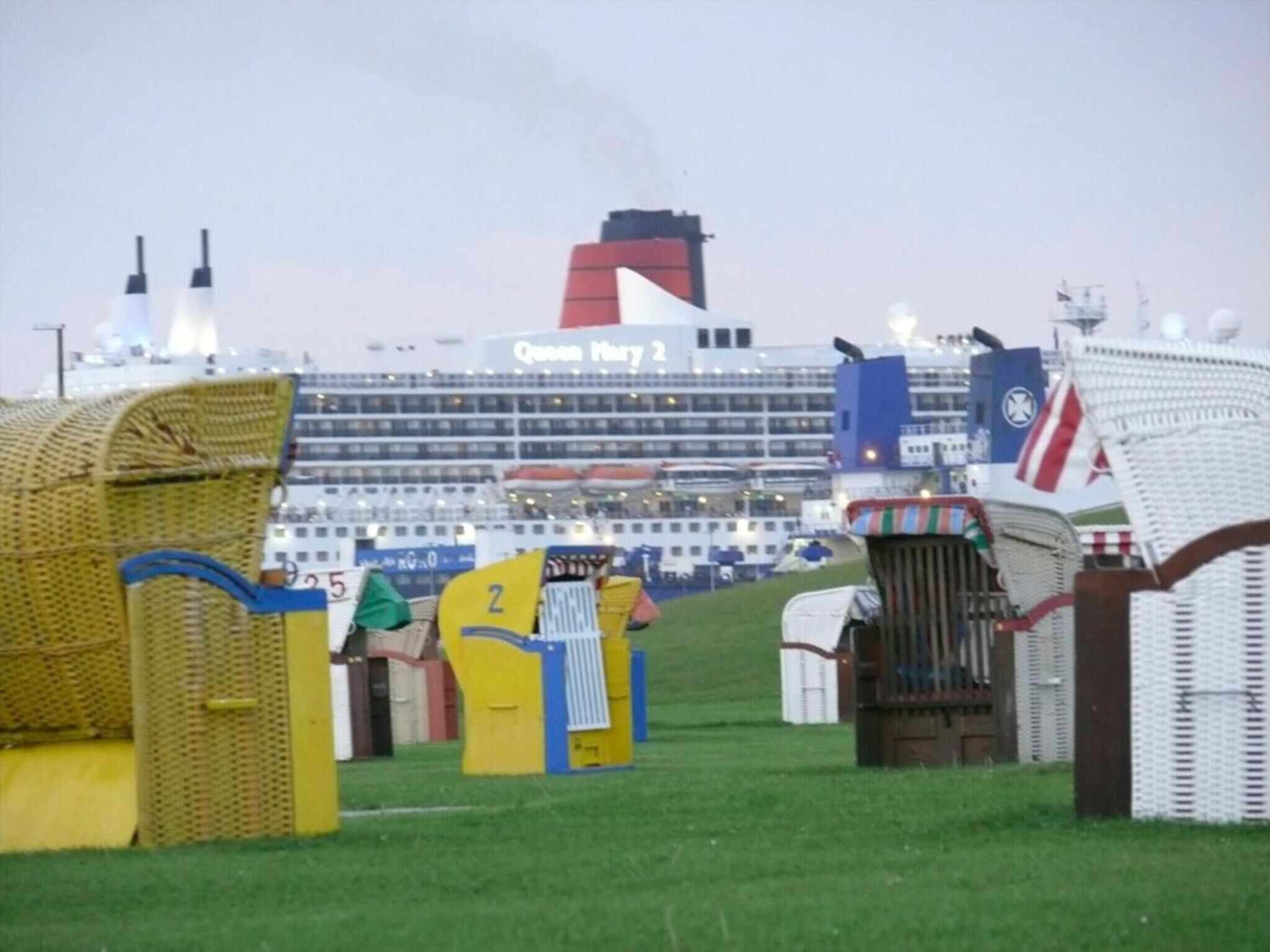 Un gran crucero amarrado en un puerto, con varias cubiertas y botes salvavidas a la vista.