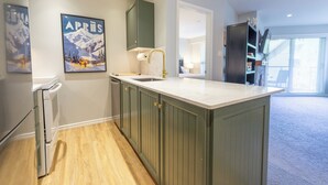 A modern kitchen with a central island, wooden cabinets, and a built-in oven. - Aspens #358 Prime Ski-in Ski-out Location! Pool, Hot tubs, BBQ, sleeps 6 (Whistler)