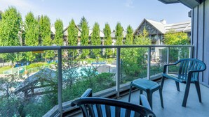 A balcony with two chairs and a table, overlooking a pool and buildings. - Aspens #358 Prime Ski-in Ski-out Location! Pool, Hot tubs, BBQ, sleeps 6 (Whistler)