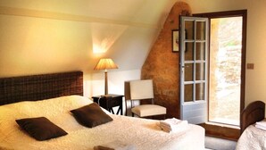 Un dormitorio con una cama grande, una silla, una mesa y una ventana con vistas.