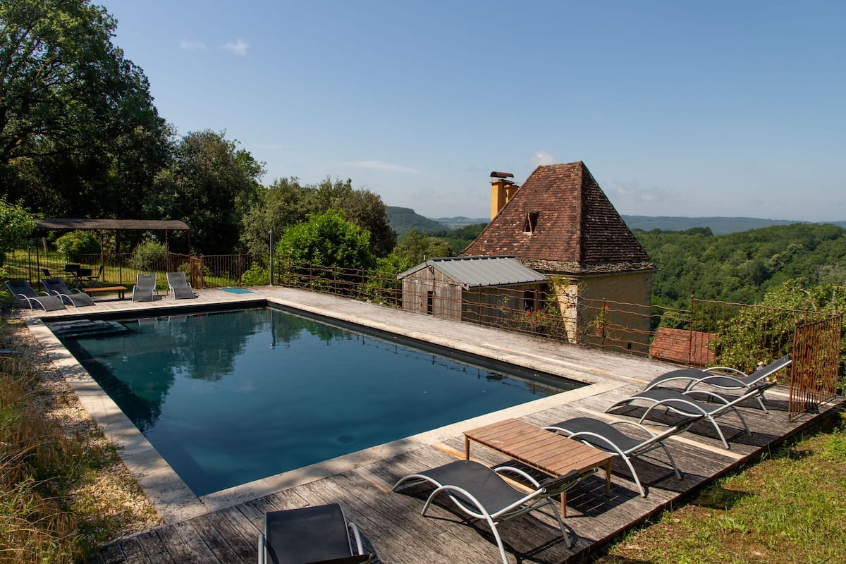 Une piscine rectangulaire dotée d’une terrasse en bois et de chaises longues.