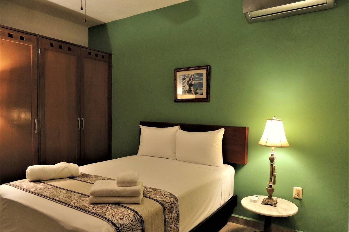 A hotel room with a bed, a nightstand, a lamp, and a wardrobe.