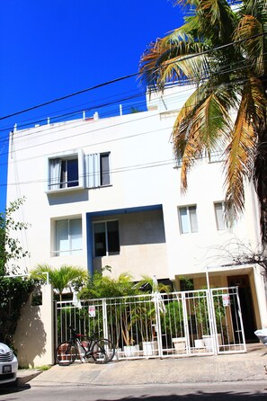 Un edificio blanco con varias ventanas y una entrada protegida por una puerta.
