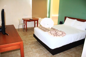 Una habitación de hotel con cama, escritorio, silla y televisión.