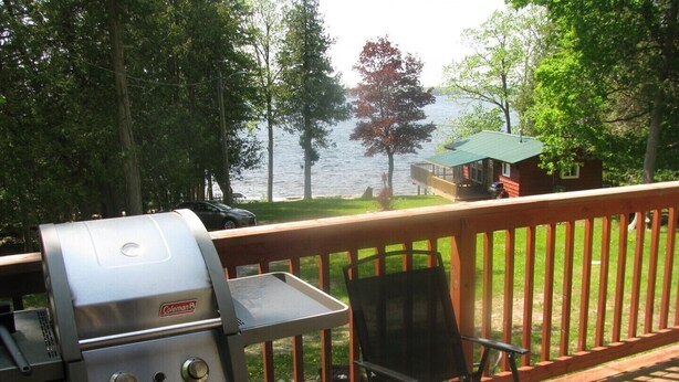 Eine Terrasse mit Grill, einem Stuhl und Blick auf einen See.