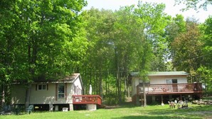 Eine Hütte mit Veranda und Terrasse, umgeben von Bäumen.